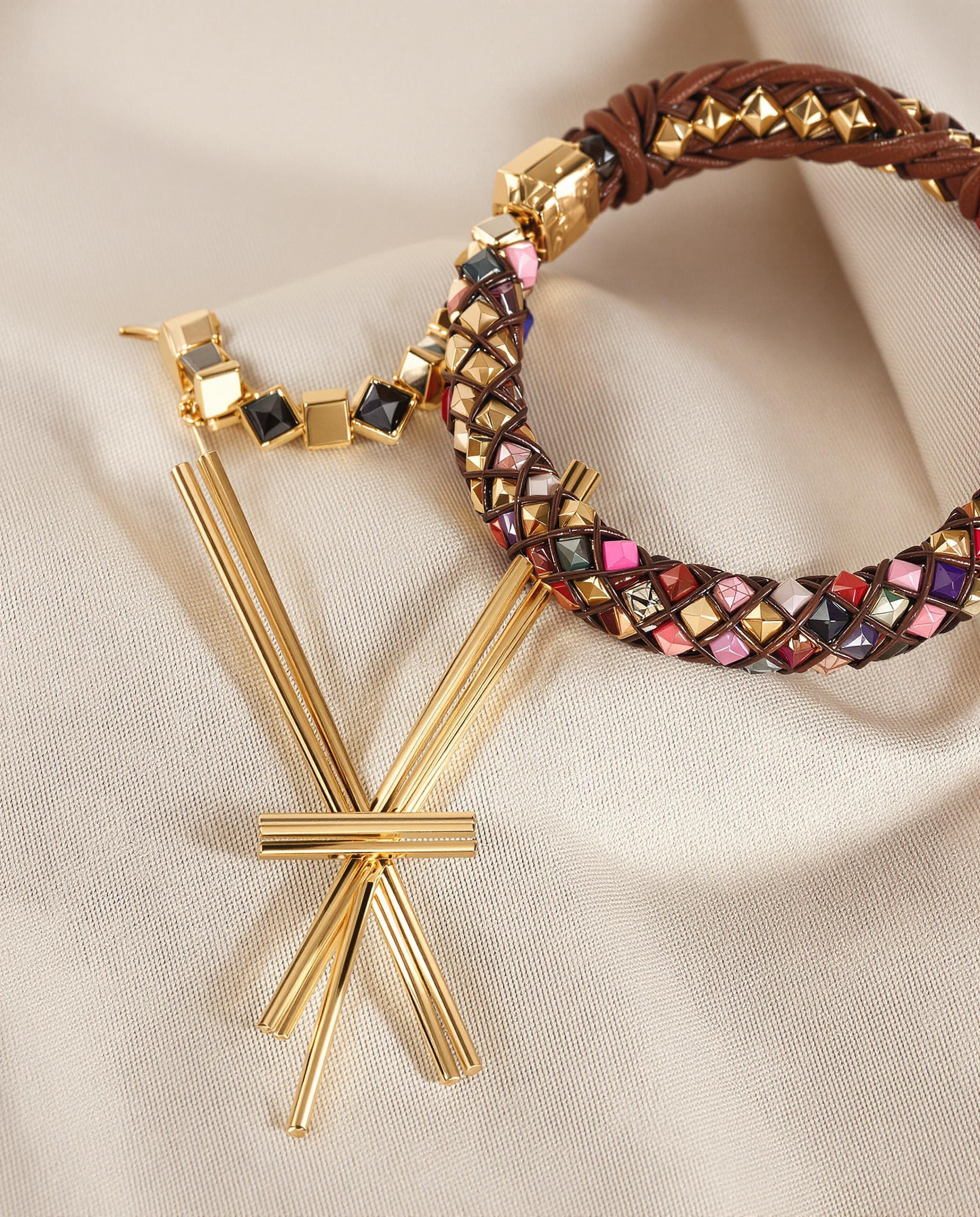 Bracelet en perles et cuir, collier en or et macramé sur tissu uni.