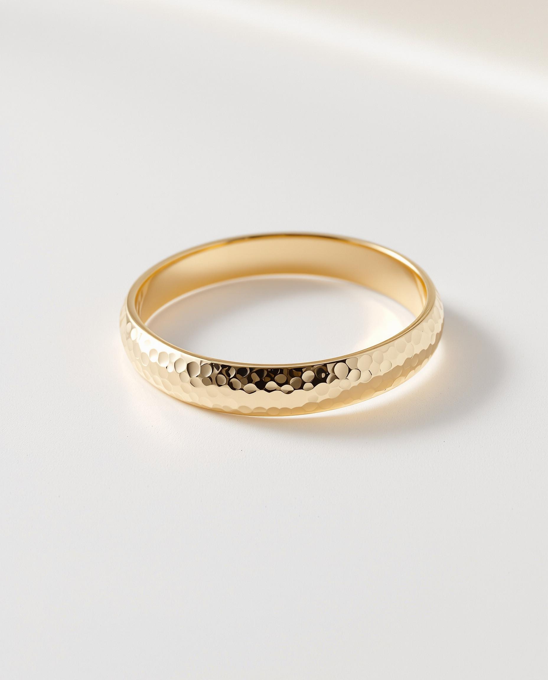 Bracelet jonc martelé en plaqué or posé sur fond blanc