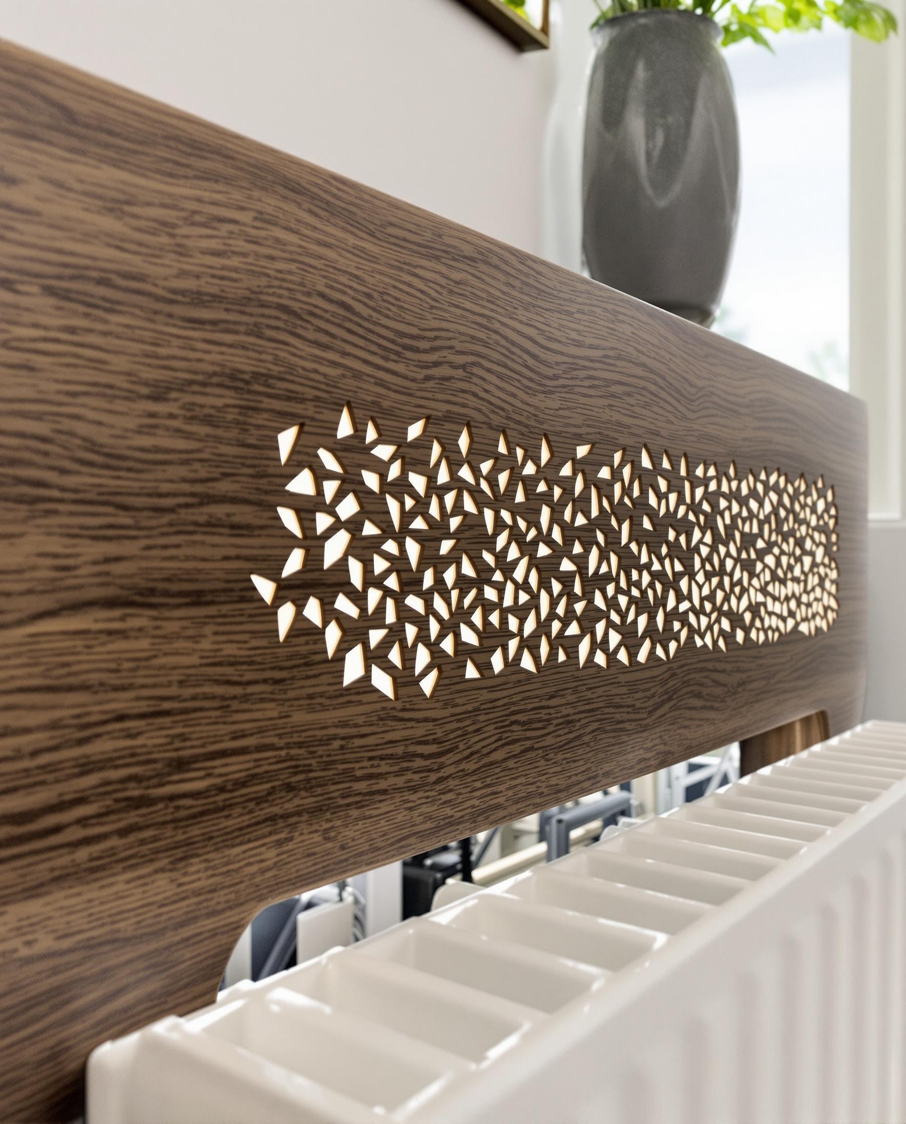Plan serré d’un cache-radiateur ajouré en chêne foncé laissant passer la lumière sur un radiateur fonte ; détails visibles de l’ajourage et texture boisuse.