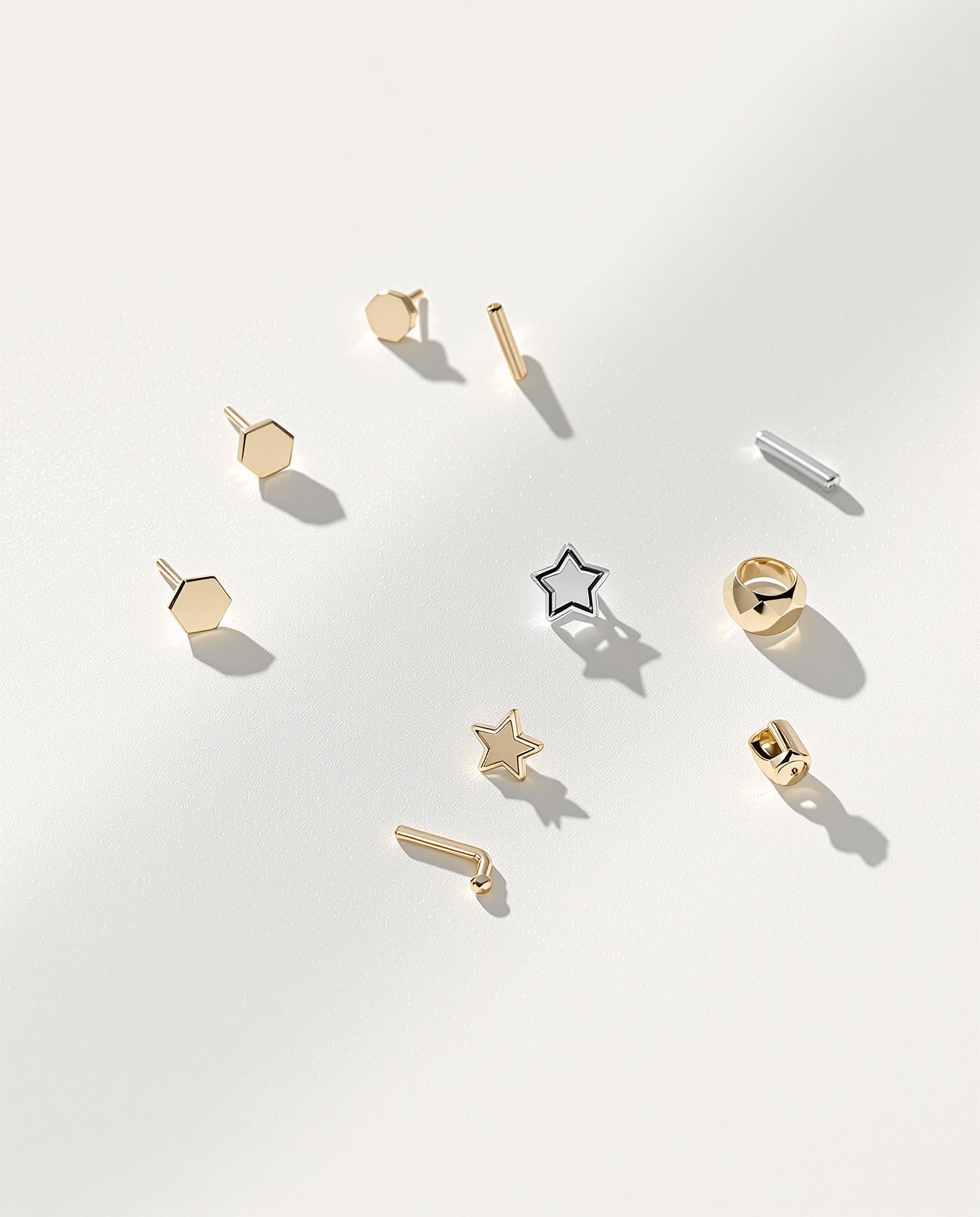 Quatre types de boucles discrètes : puces fines (diverses formes), mini créoles or/argent, ear cuff ajusté sur cartilage, piercing tragus titane doré.