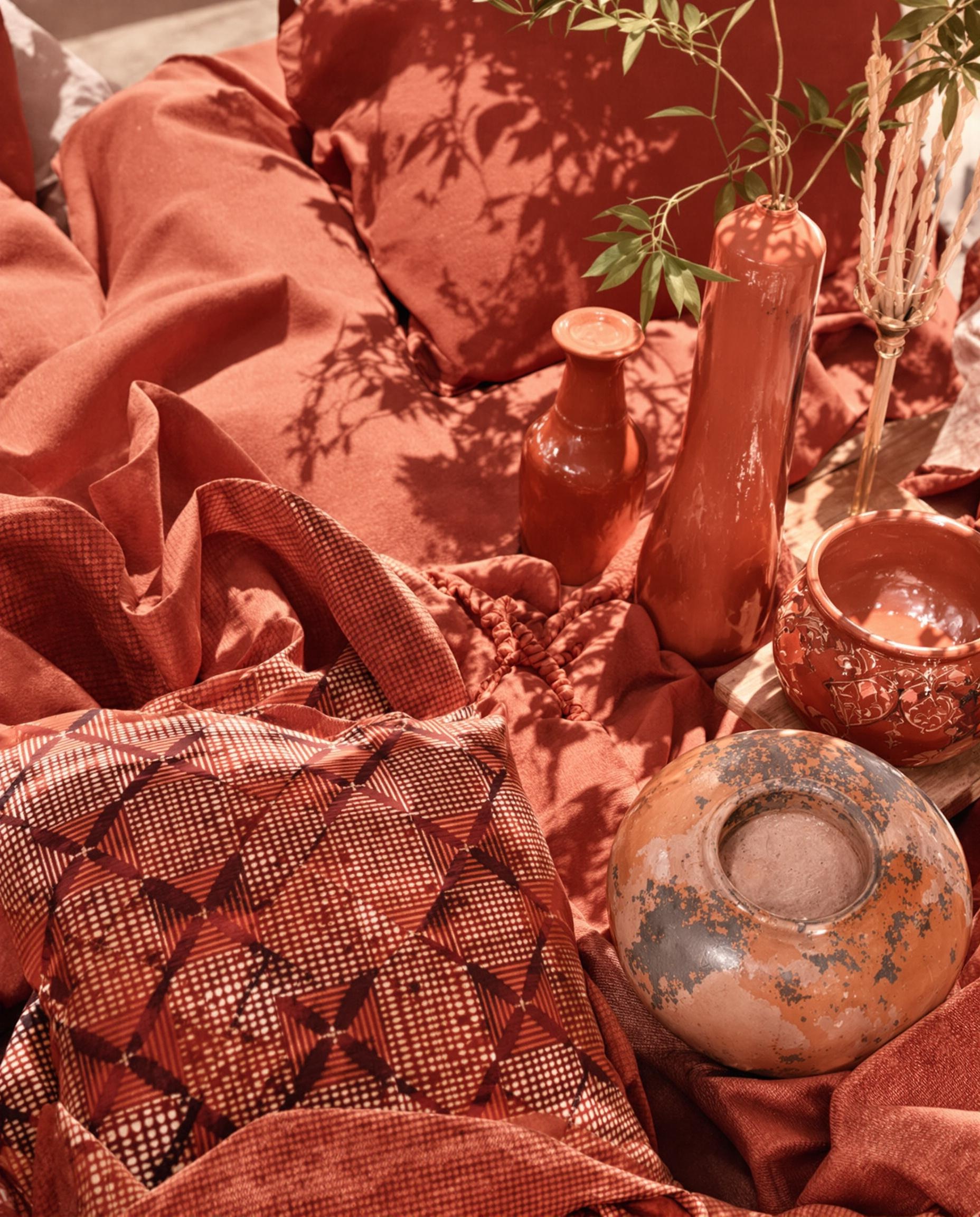 Coussins teints Marsala, bol terre cuite artisanal, accessoires rouges.