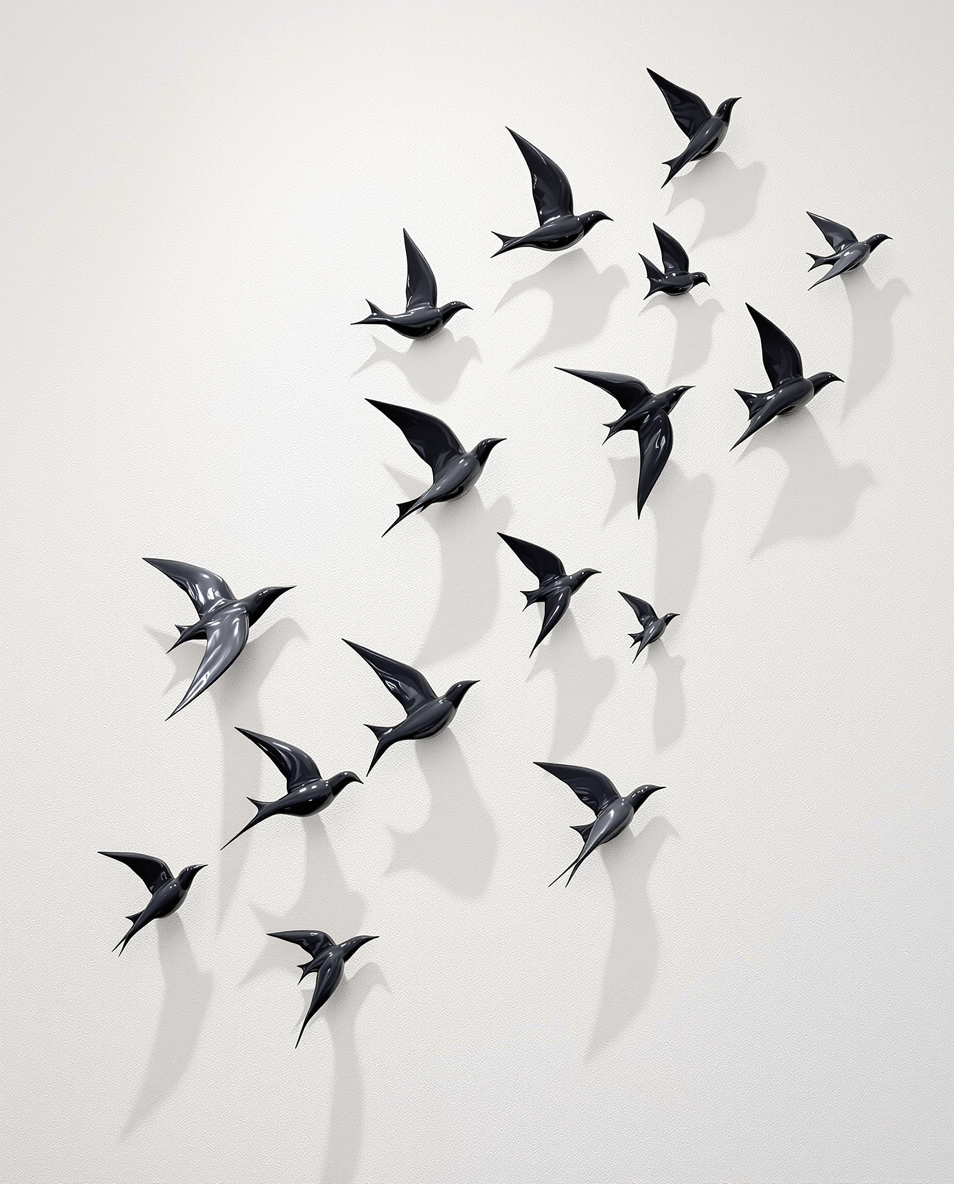 Composition murale d'hirondelles en céramique noire volant sur un mur blanc texturé
