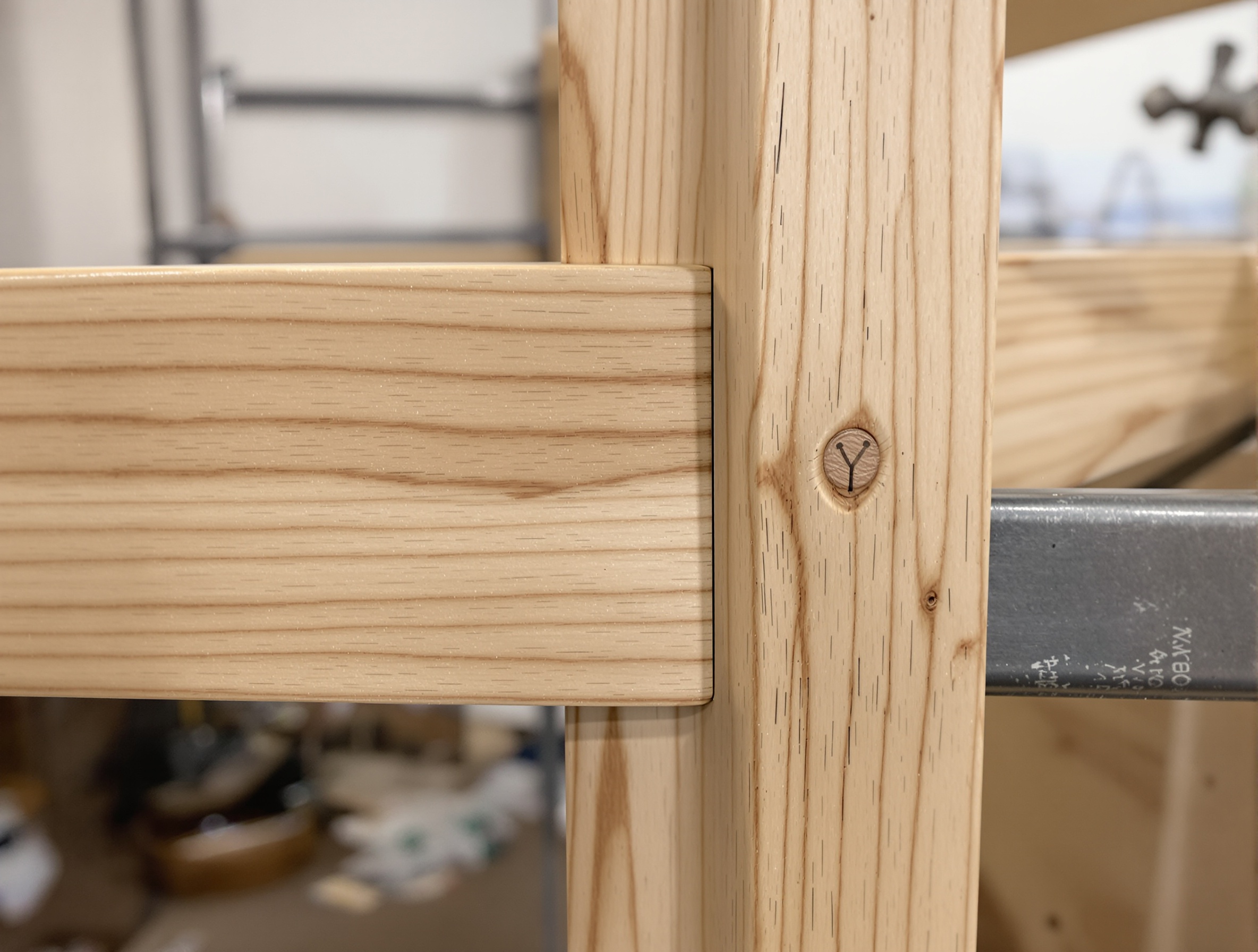 Détail contraste menuiserie bois massif impeccable et soudure grossière métal bon marché sur lit superposé