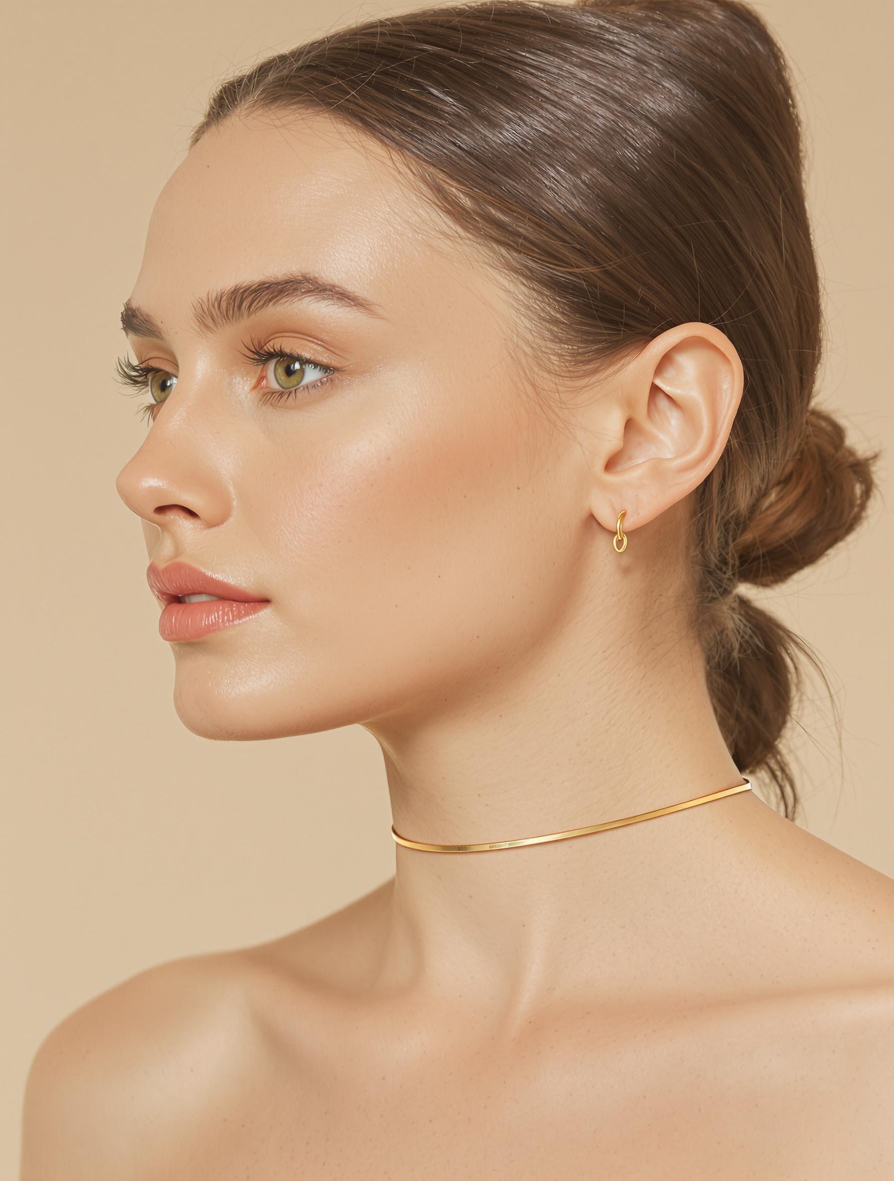 Femme portant un ras-de-cou or fin minimaliste, fond neutre