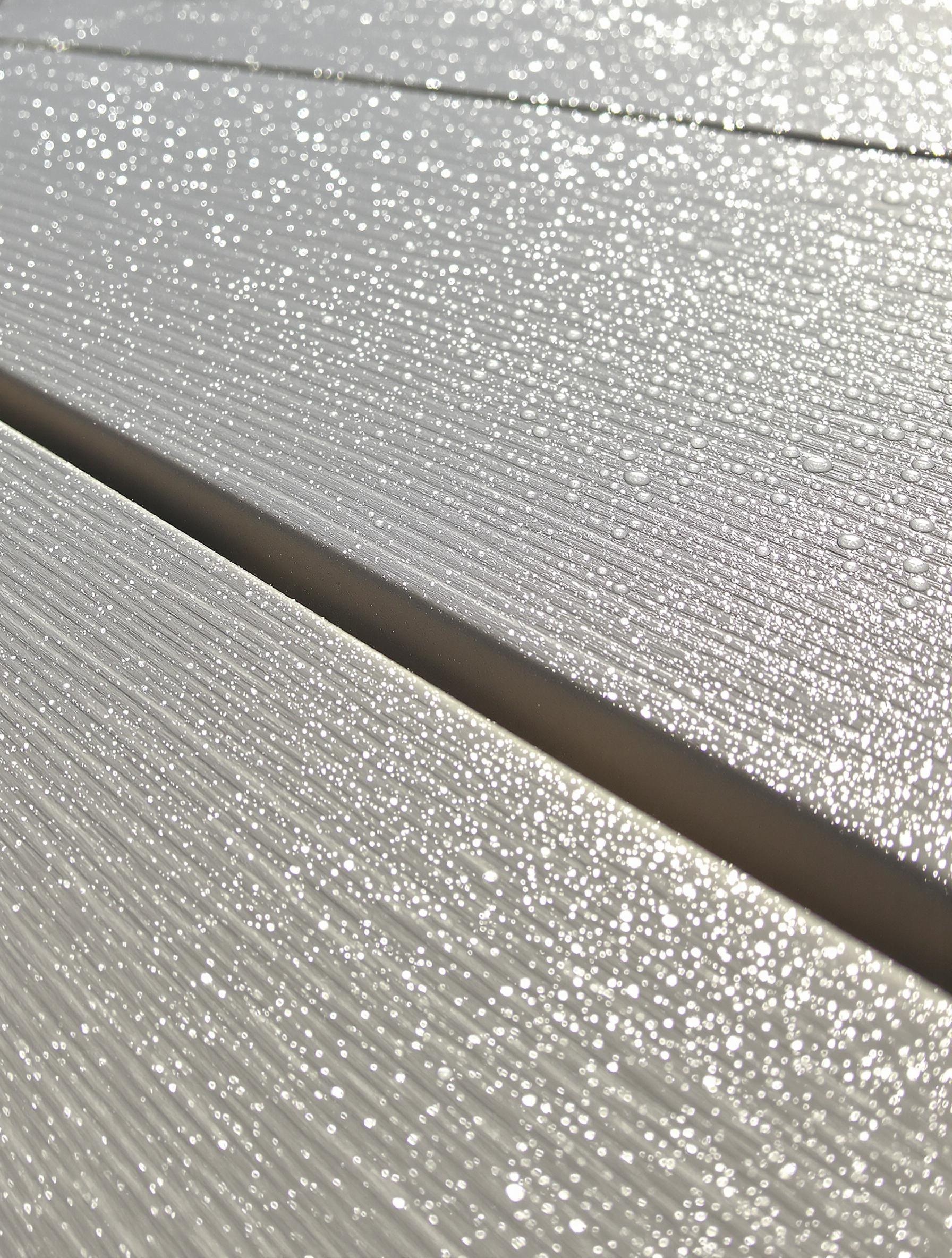 gros plan surface de terrasse composite au soleil gouttes d'eau perlees