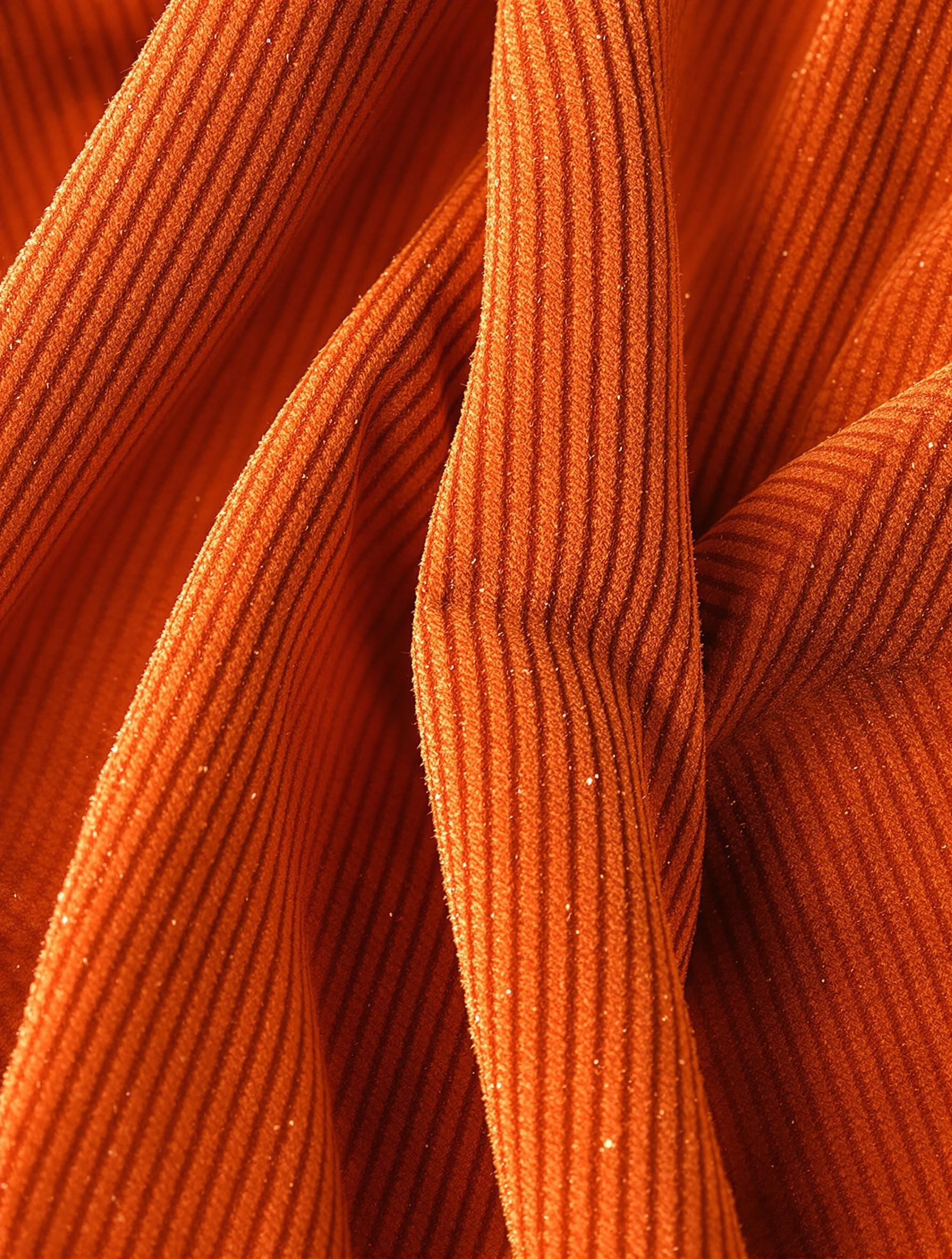 Texture velours côtelé orange brûlé avec reflet sophistiqué.