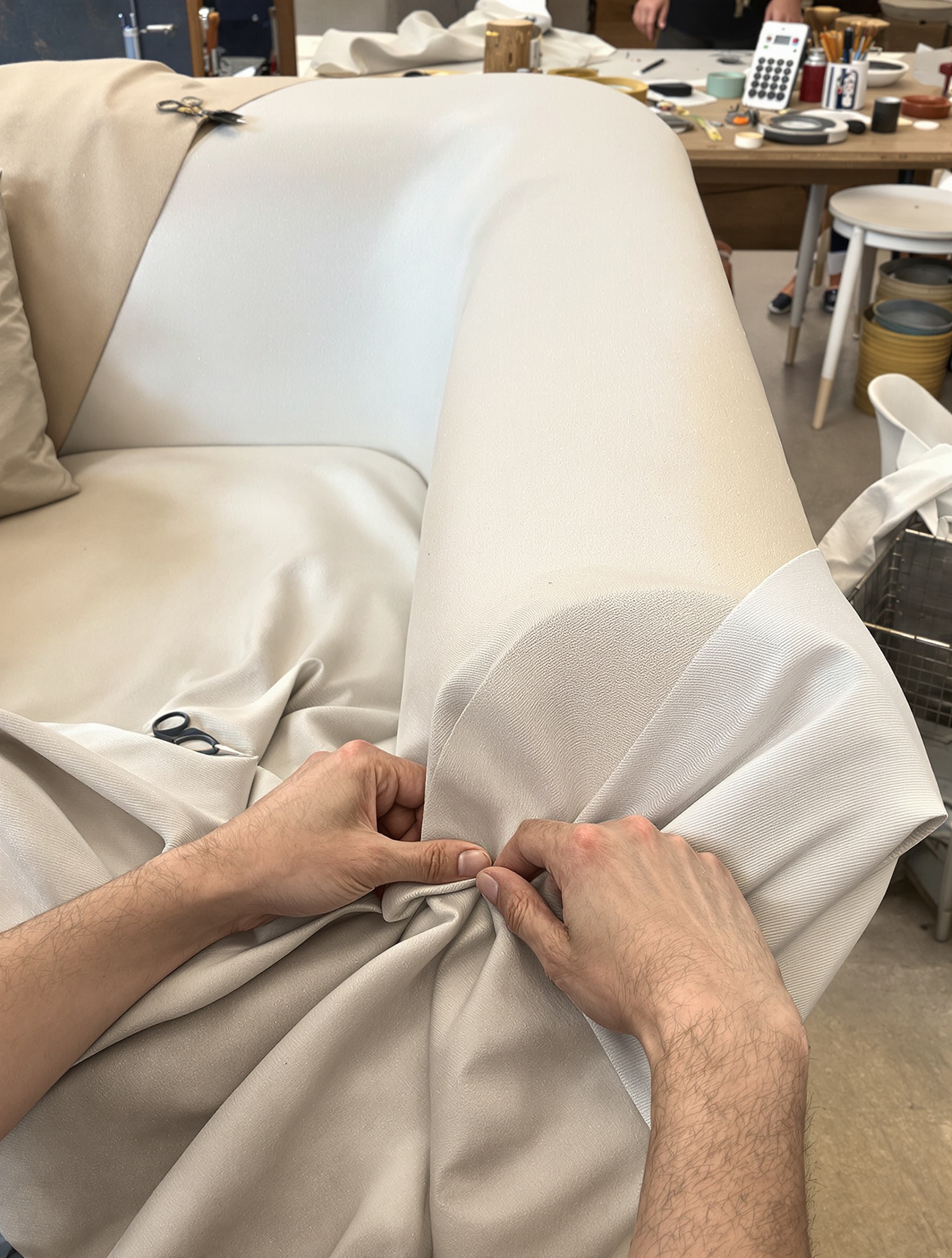 Artisan tapissier rénovant une housse de canapé Ghost dans son atelier.