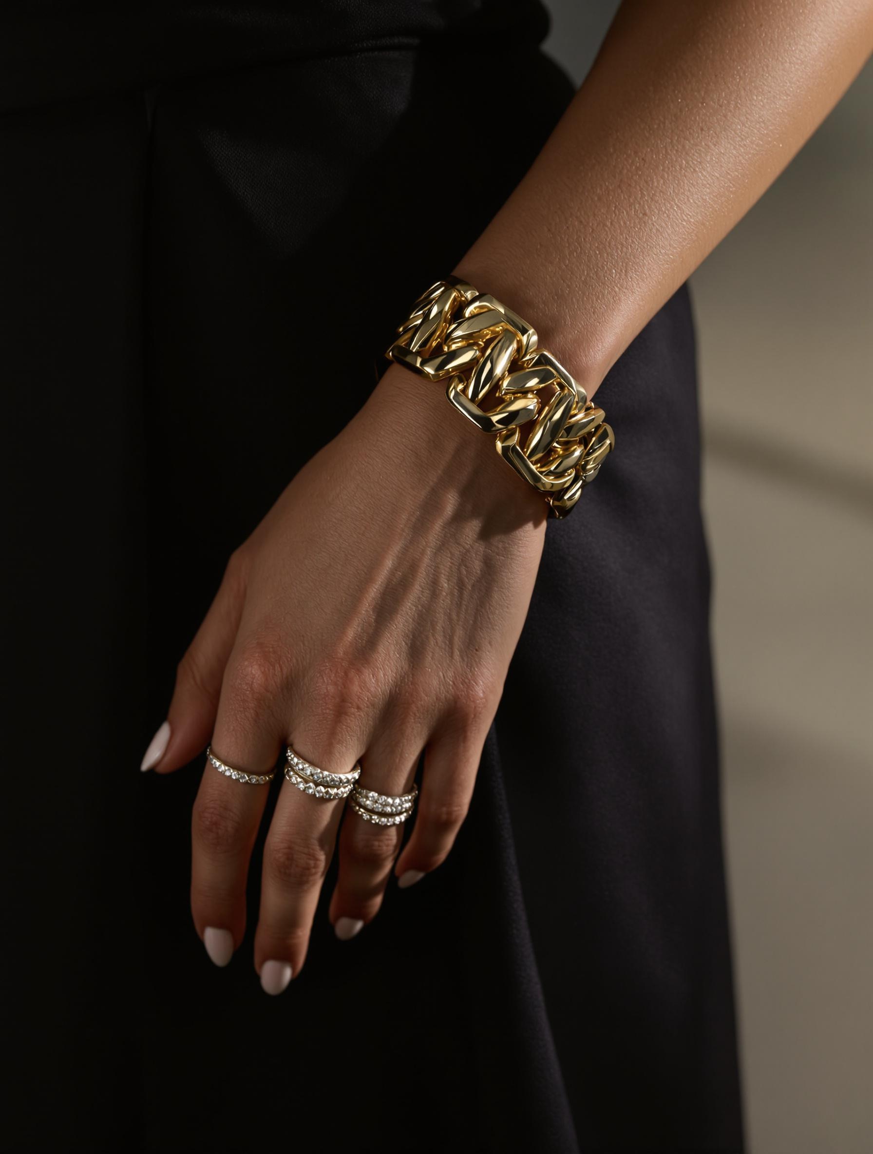 Poignet avec bracelet massif en or et bagues fines argentées.