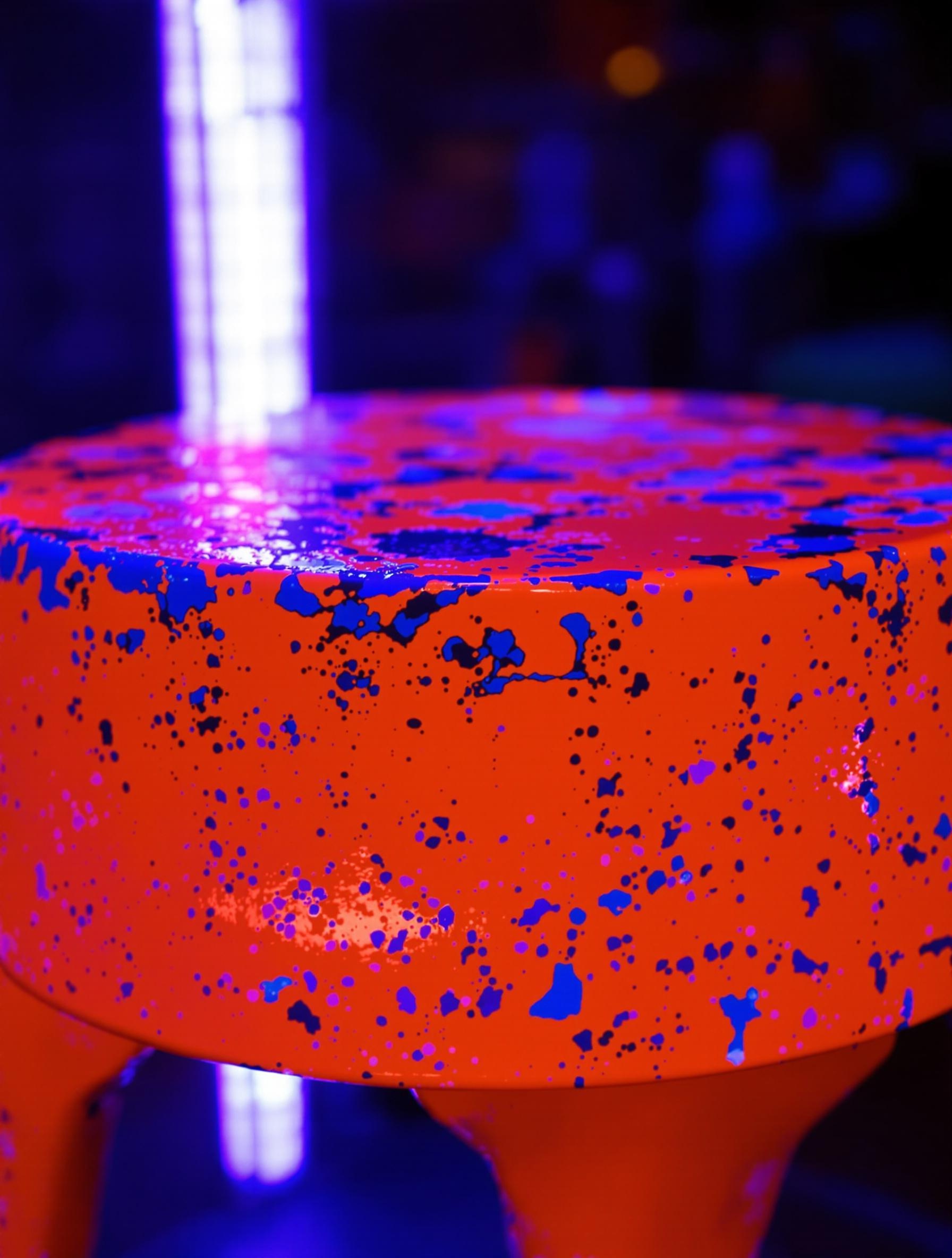 Tabouret orange néon patiné sous lampe UV.